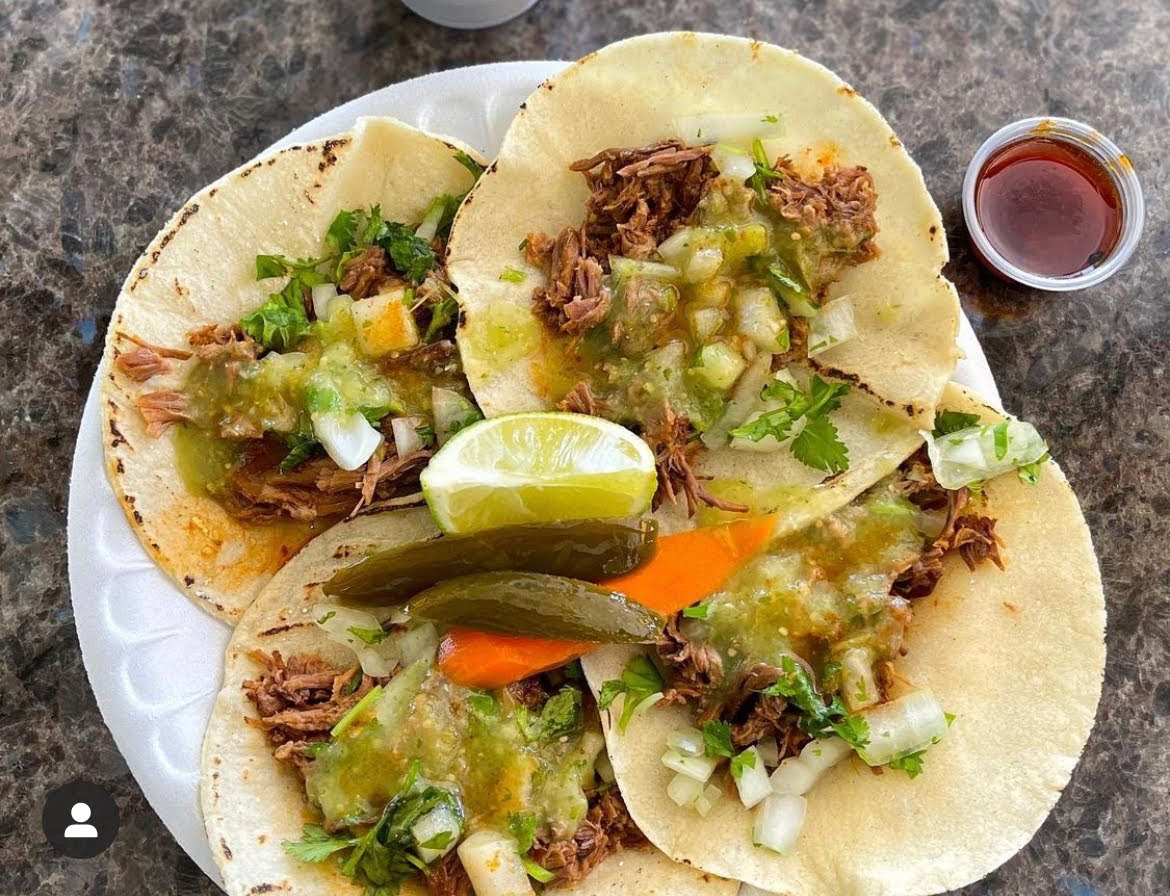 Three tacos topped with salsa verde, onion, and cilantro